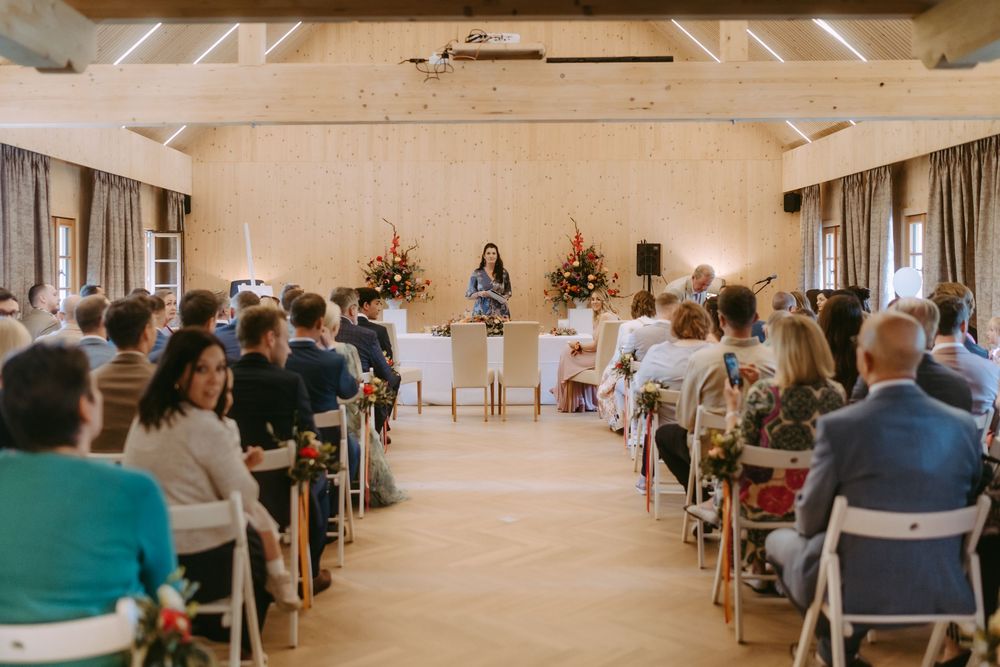 Indoor wedding ceremony setup with rows of chairs and floral decorations.