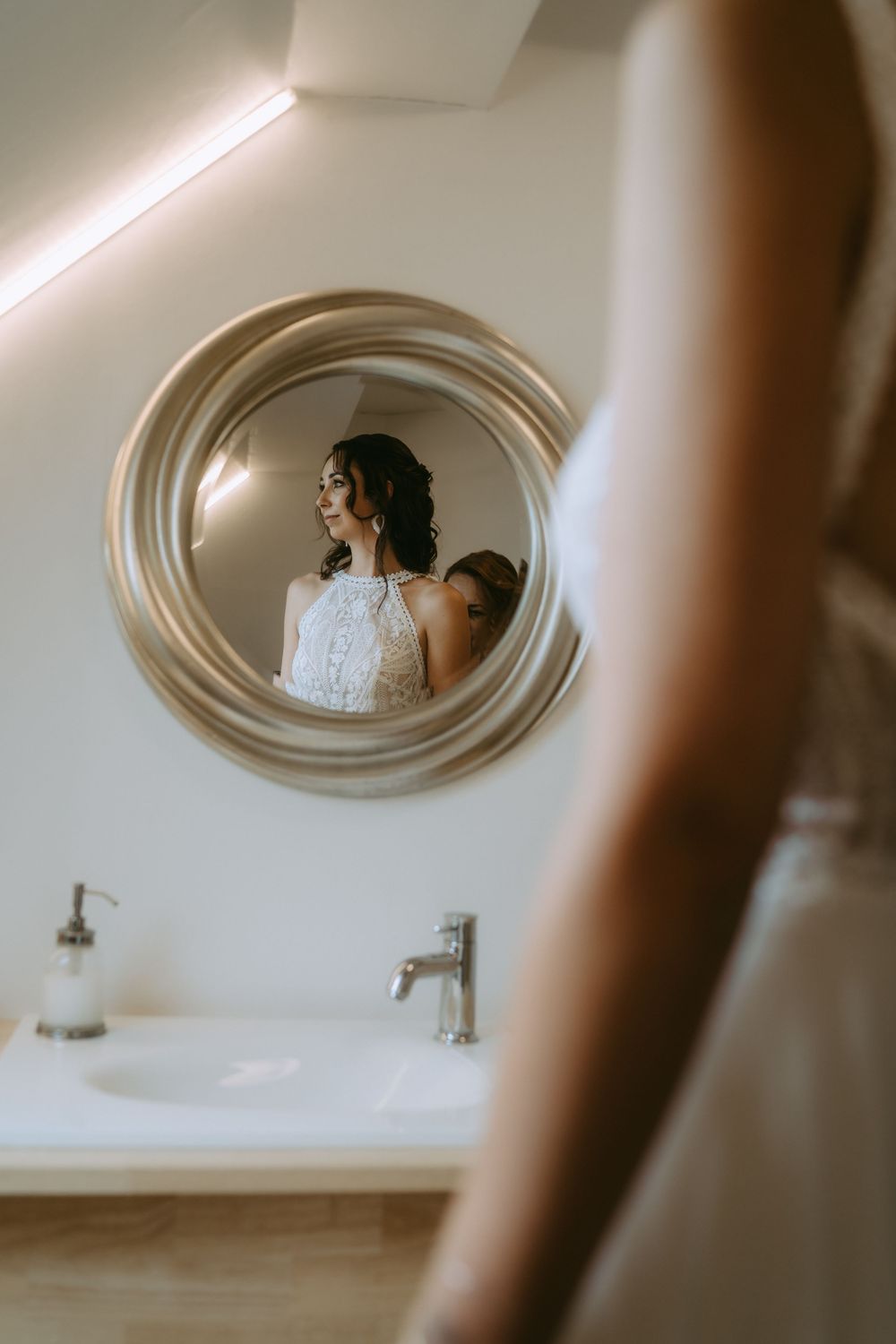Artistic mirror reflection of bride in white lace dress.