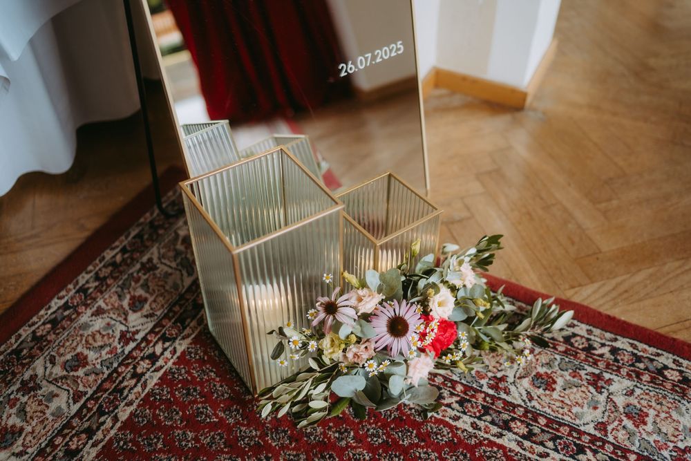 Wedding venue detail showing decorative lanterns and floral arrangements on oriental carpet.