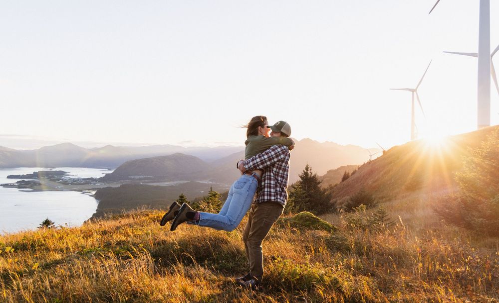 A group of hikers enjoy a scenic mountain overlook at sunset with golden light illuminating the landscape.