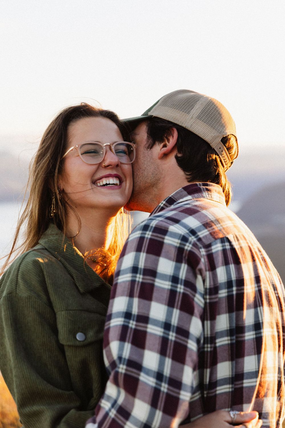Romantic couple sharing intimate moments at sunset in a series of candid photos wearing plaid and olive green.