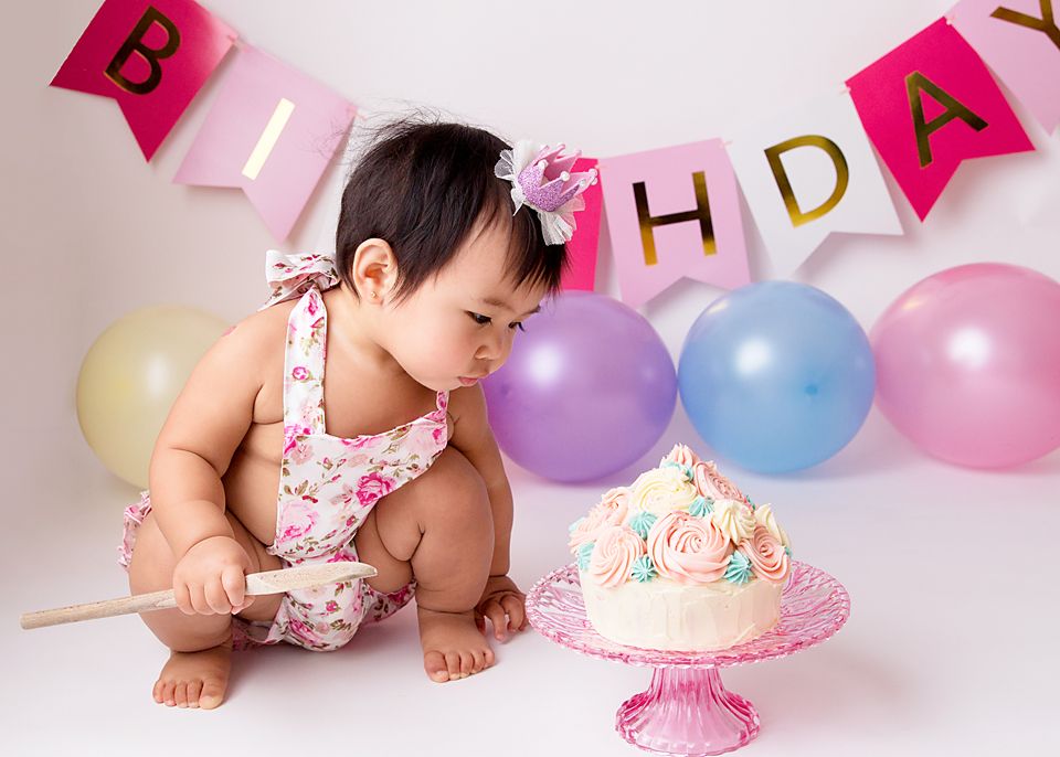 Pink and gold birthday banner display with pastel balloons and cake setup.