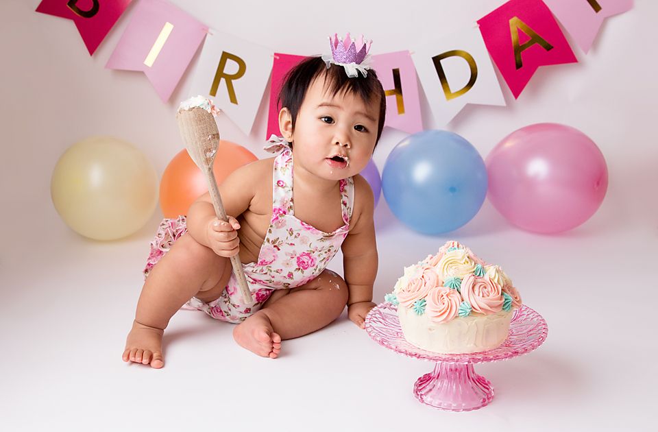 Birthday celebration setup with colorful balloons and pink 'BIRTHDAY' banner against white backdrop.