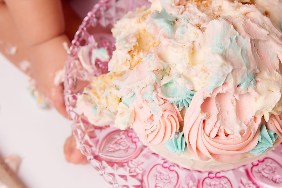 Close-up of pink and teal decorated birthday cake with frosting rosettes.