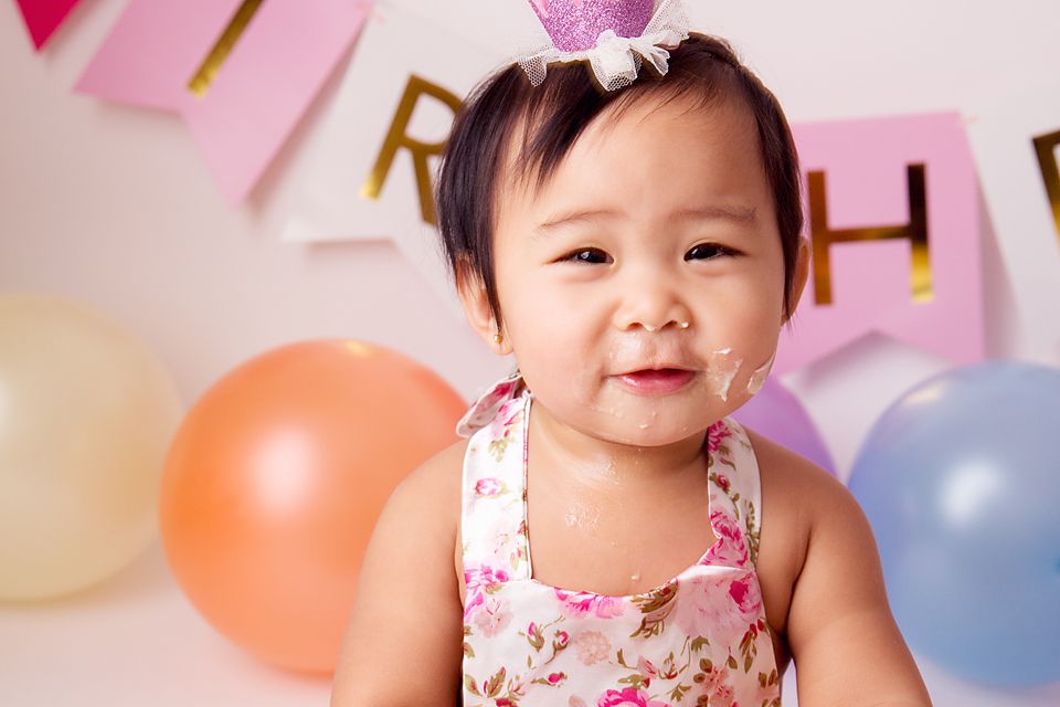 Birthday celebration setup with pink banners, balloons, and cake for a first birthday party.