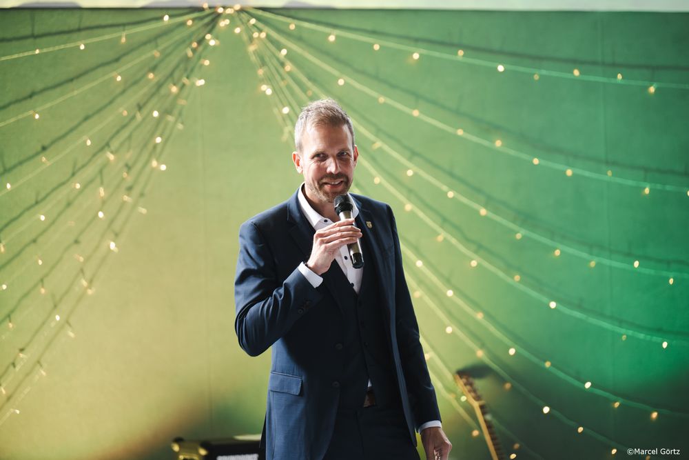 String lights create a festive atmosphere as performers sing during an indoor choral performance.