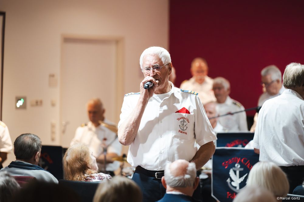 A group of seniors in white shirts gather in a room for a social activity or event.