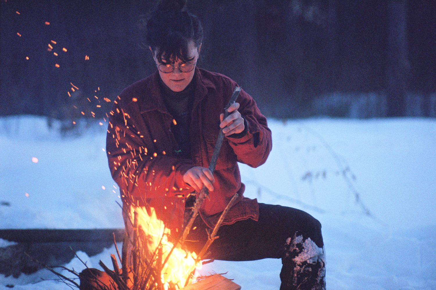 A person builds a fire on a snowy day.