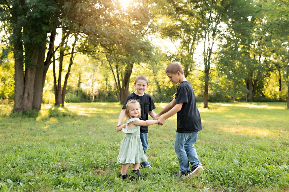 Children playing ring around the rosey at golden hour during family photos in Oconomowoc Wisconsin