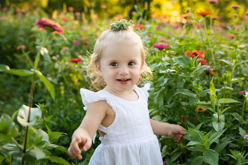 Toddler smiling among colorful flowers during summer mini sessions at First Roots Flower Farm in Oconomowoc, Wisconsin.