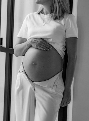 Artistic black and white series showing a pregnant woman in white clothing against a minimalist background.