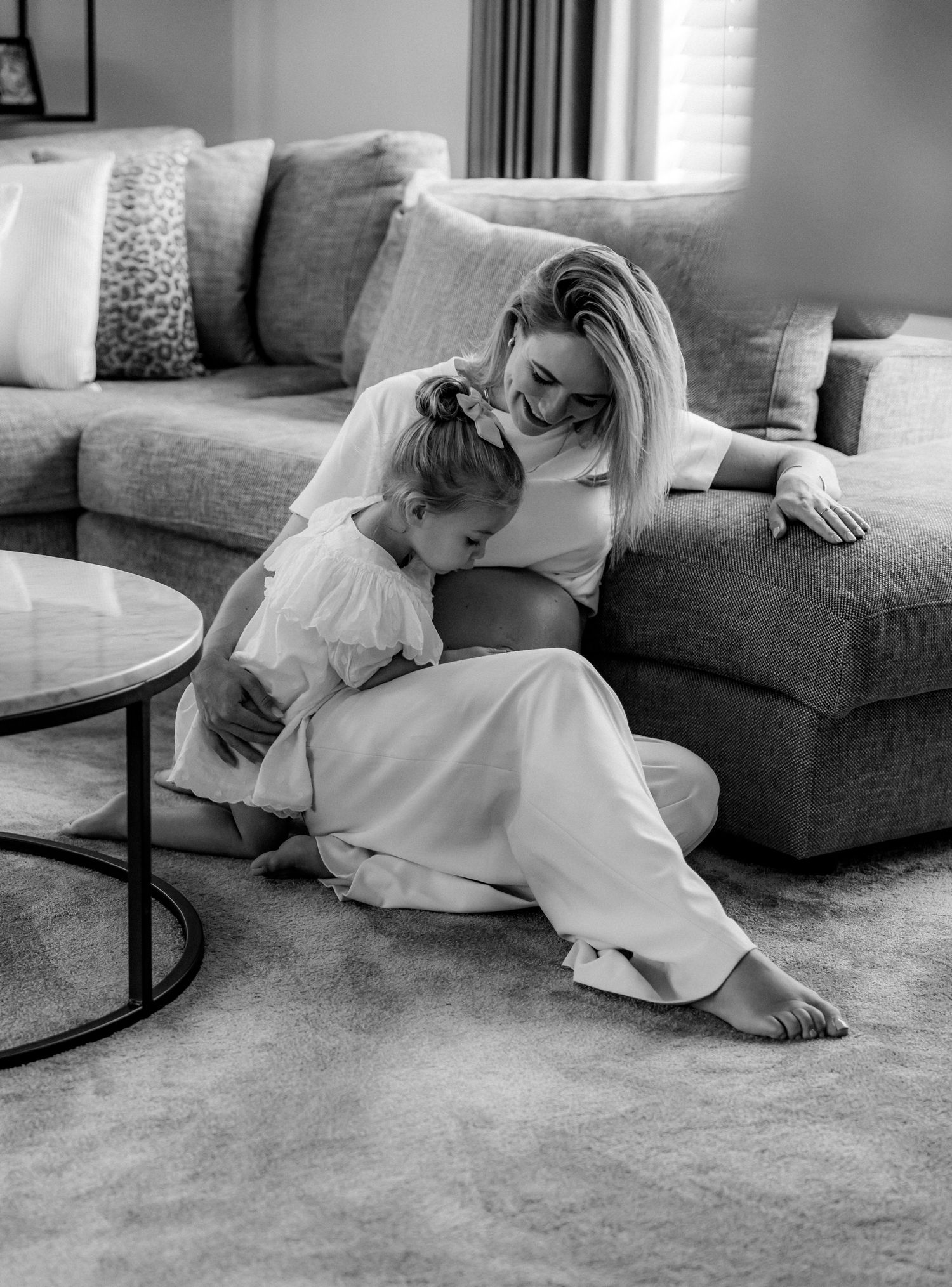 A heartwarming black and white photo of parent and child sharing a quiet moment on a gray couch.