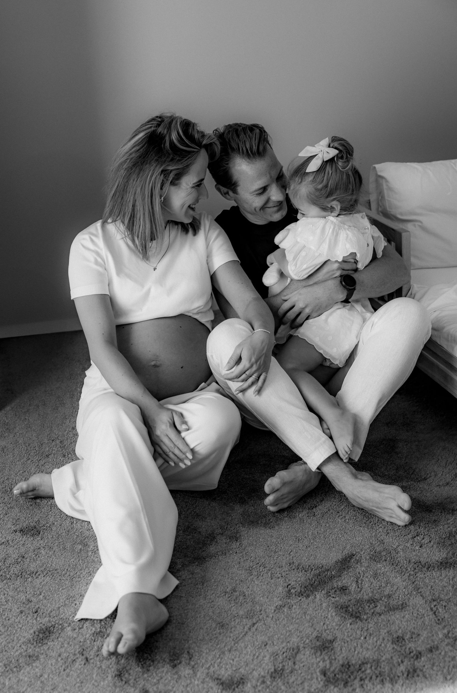 Black and white photo of a family sharing laughter while sitting together on carpeted floor.