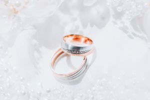Two rose gold and silver wedding rings with textured details rest on a white textured surface.
Emlékek, amelyek egy életre szólnak