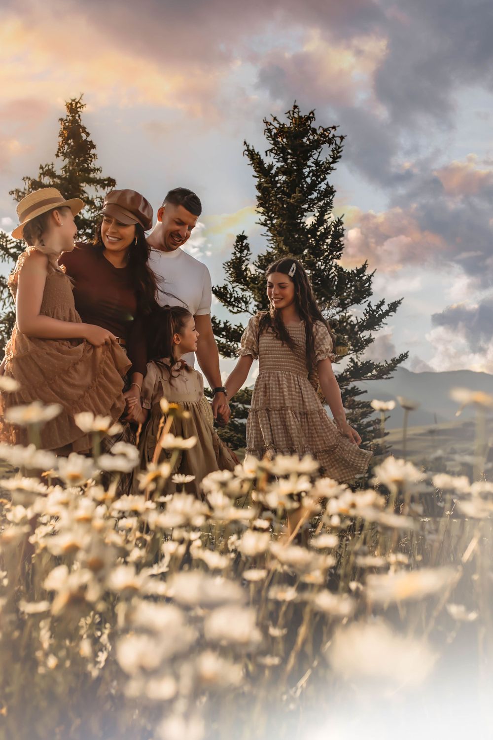 Family gathering among wildflowers at sunset with mountains in background.