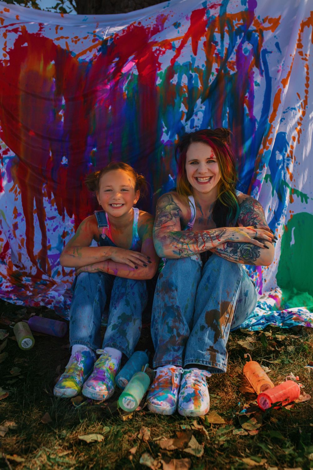 Playful paint splatter photoshoot with colorful backdrop and matching shoes.