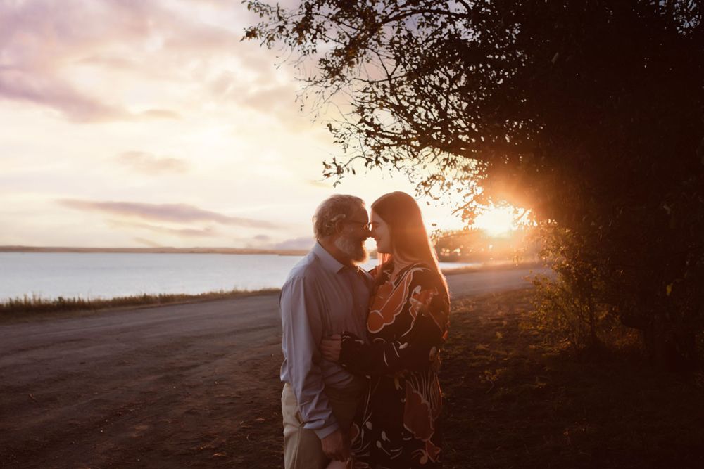 Romantic silhouette of a couple embracing at sunset on a coastal road.
