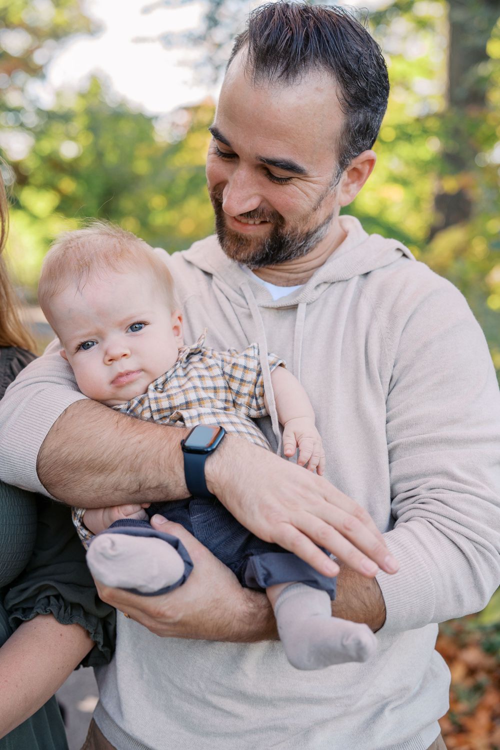 A tender moment captured between parent and baby outdoors in autumn setting.