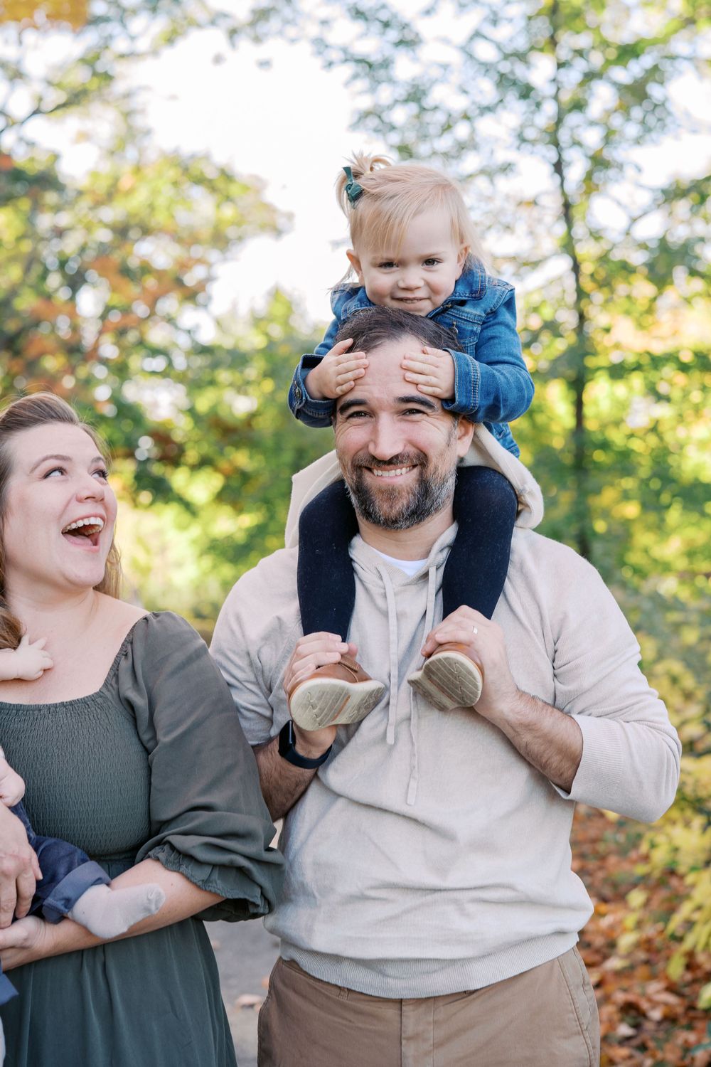 A joyful outdoor family moment captured during autumn with trees in the background.