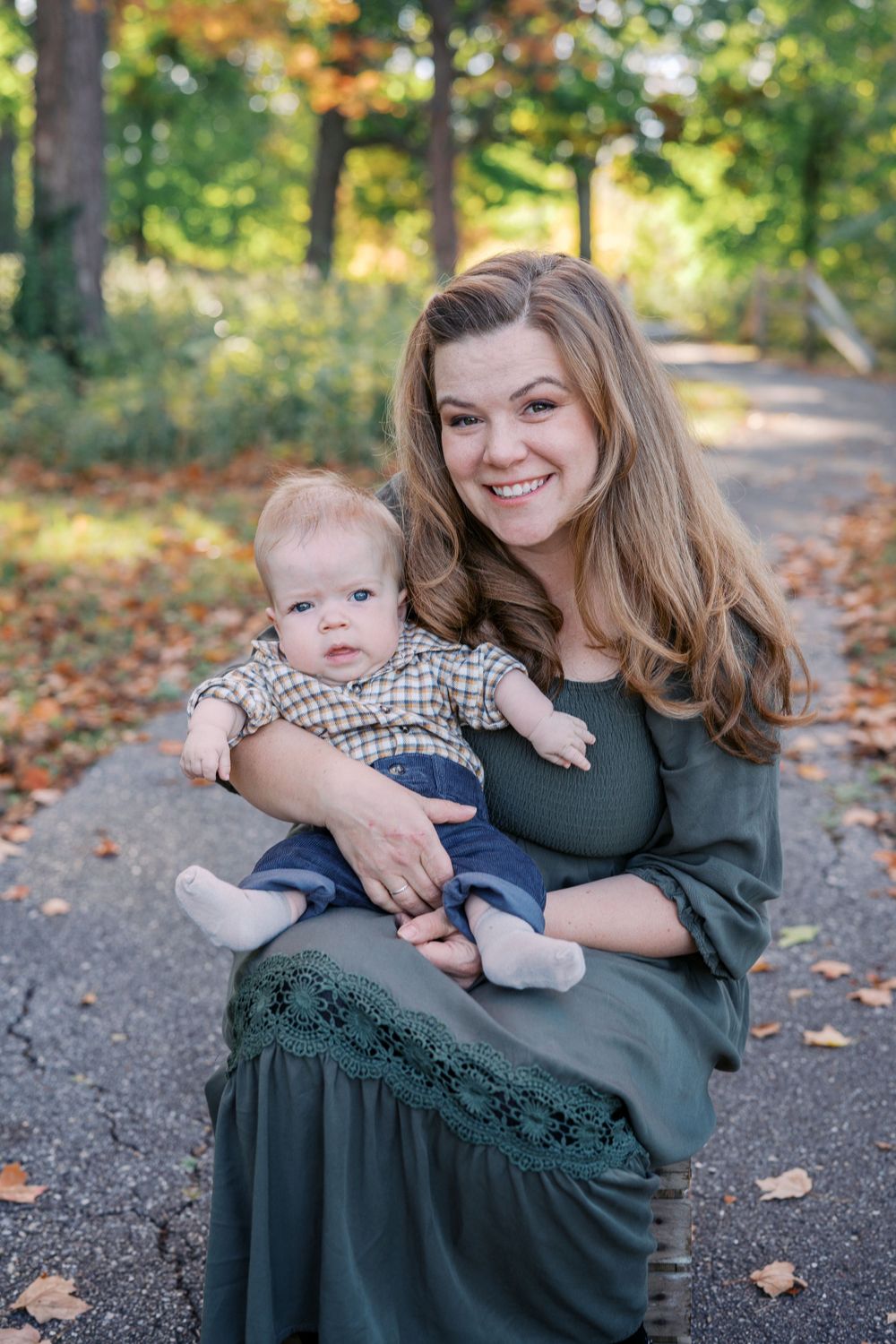 A tender moment between parent and baby on an autumn path with fallen leaves.