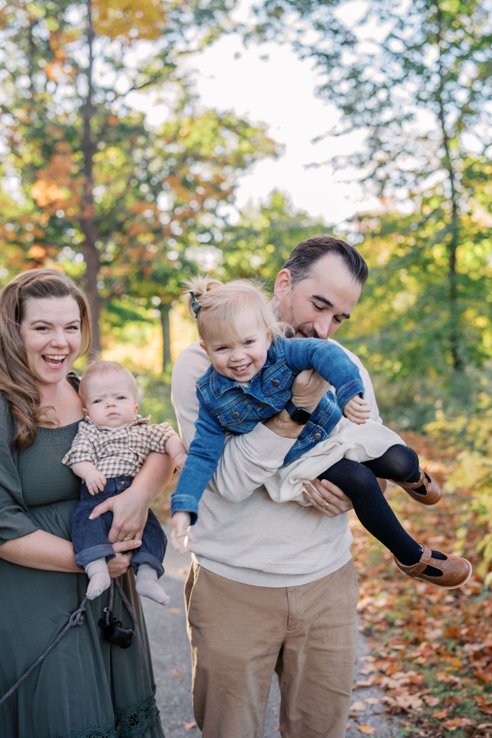 Family shares playful moments during autumn outdoor photoshoot with golden lighting.