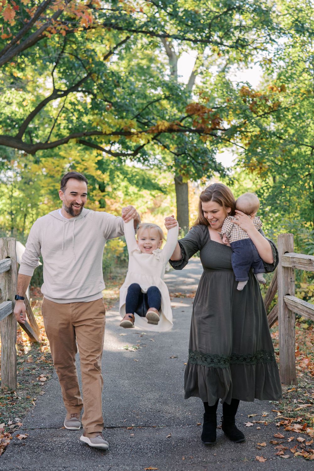 A family enjoying a playful moment on a tree-lined path during autumn.