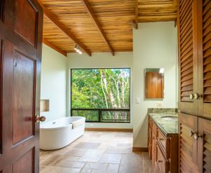 Luxury bathroom with high-end finishes, a standalone bathtub, and a window overlooking nature