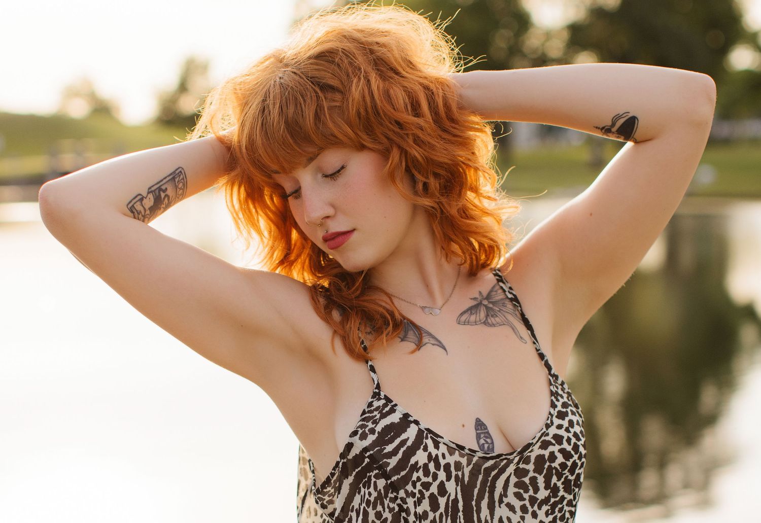 A summer portrait by the water featuring a leopard print dress and visible tattoos.