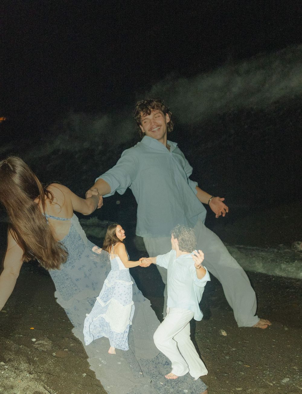 People dancing together joyfully on a dark night with atmospheric lighting creating a dreamy party scene.