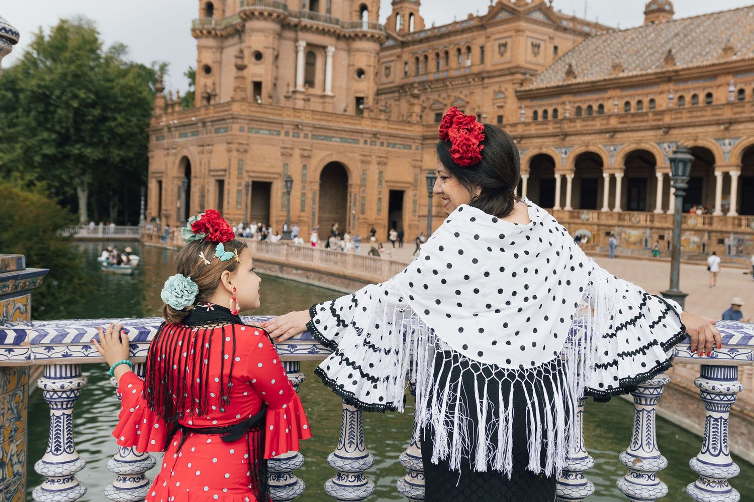 Two flamenco dancers in traditional dress admiring Plaza de España in Seville, Spain.