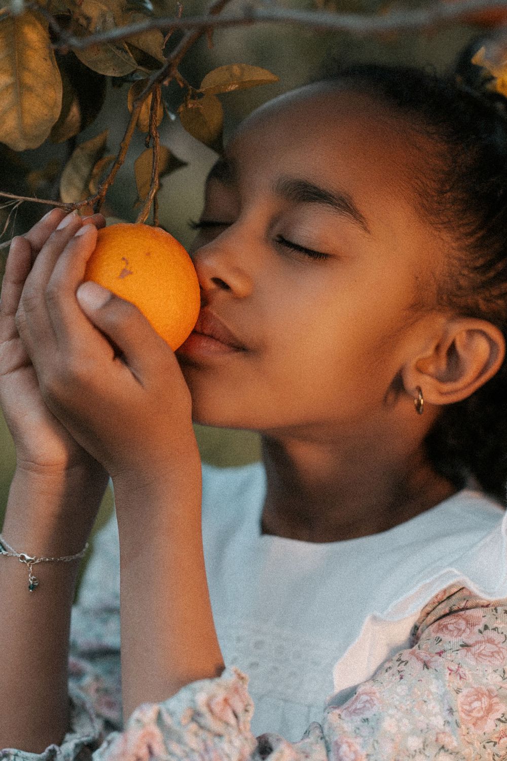 A child in a white top smells a fresh orange in a series of connected photos showing the sensory experience.