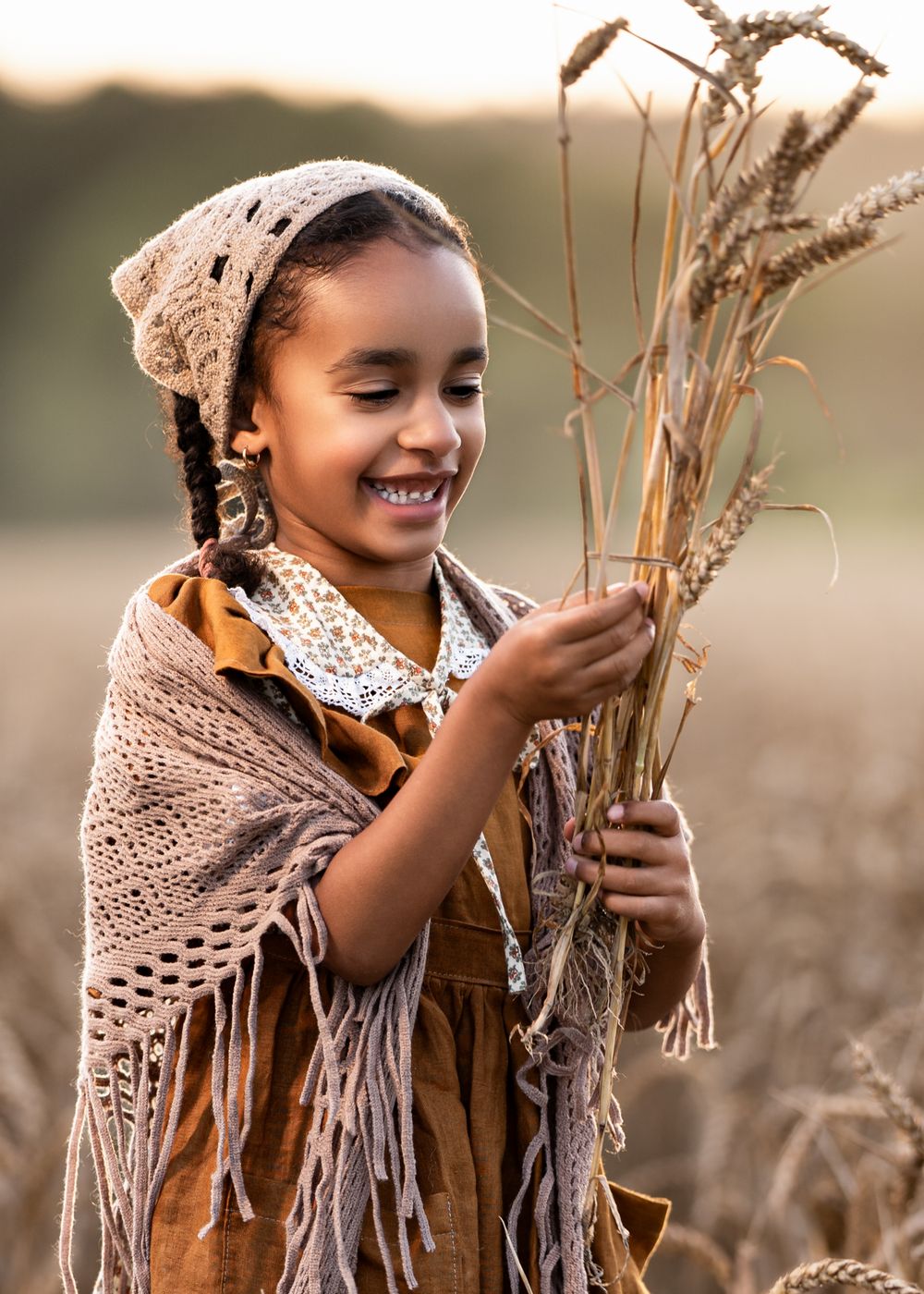 Artistic portrait with wheat stalks and vintage-styled clothing in golden afternoon light.