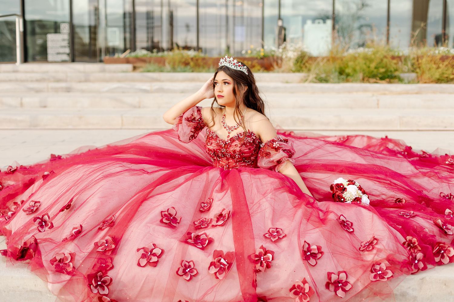 Dreamy outdoor quinceañera portrait featuring a flowing pink ball gown with rose appliques.