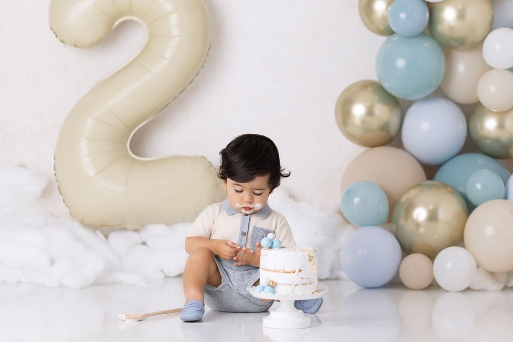 Second birthday party setup with large number 2 balloon and blue, gold, and white balloon arch arrangement.