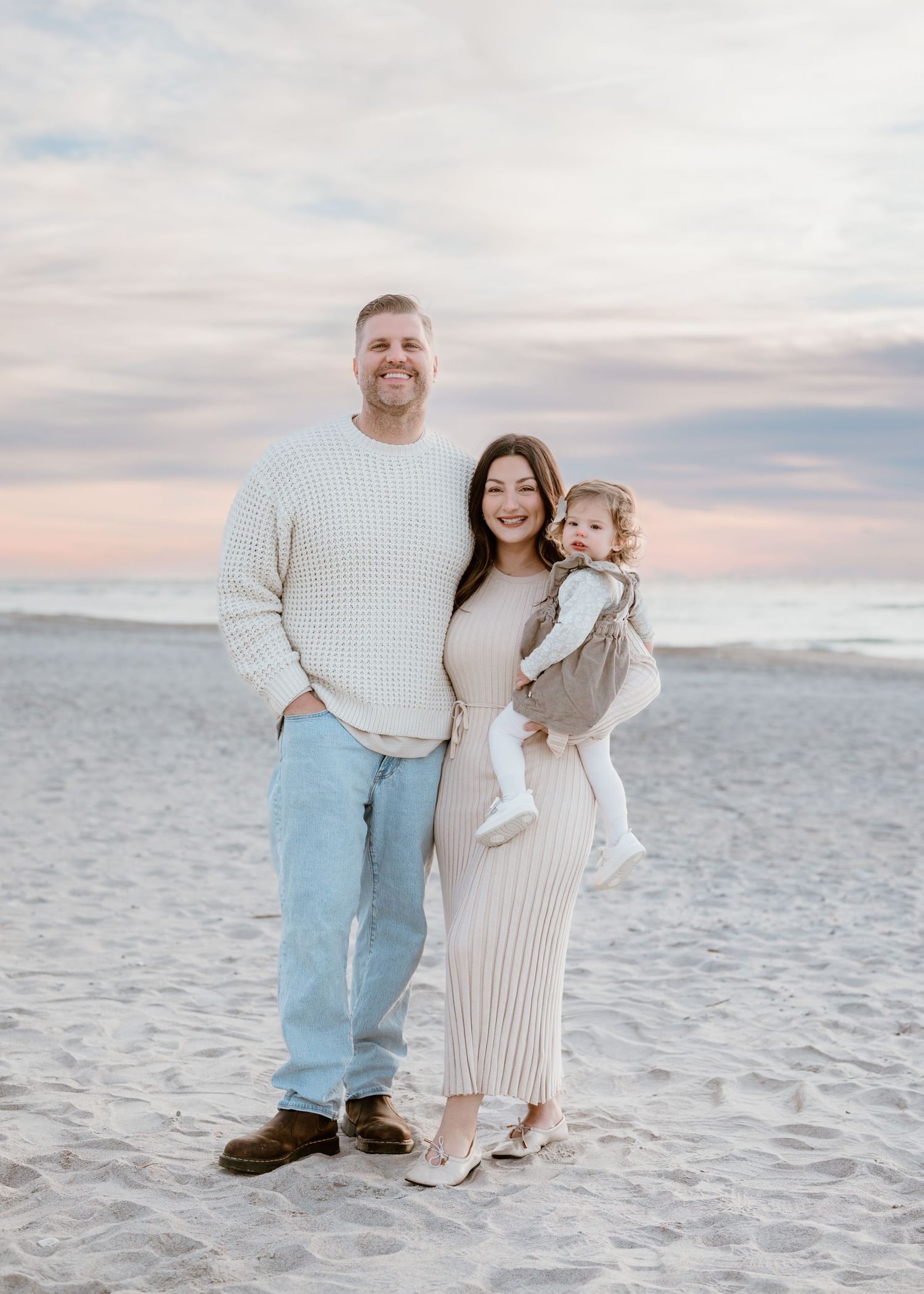 Family shares tender moments together at sunset by a wooden fence in a rustic outdoor setting.
