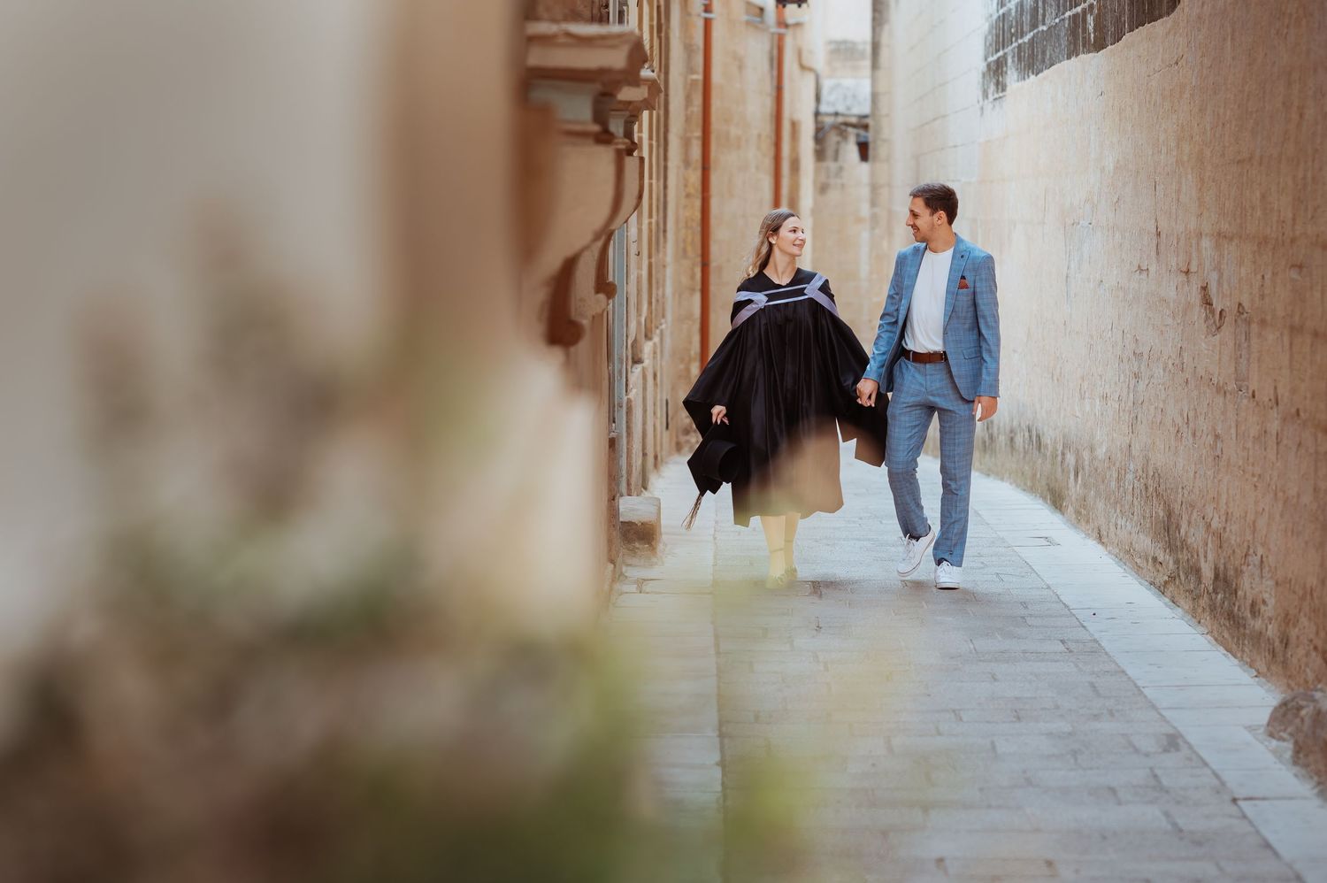 People walking through a narrow stone alleyway in an old European city.