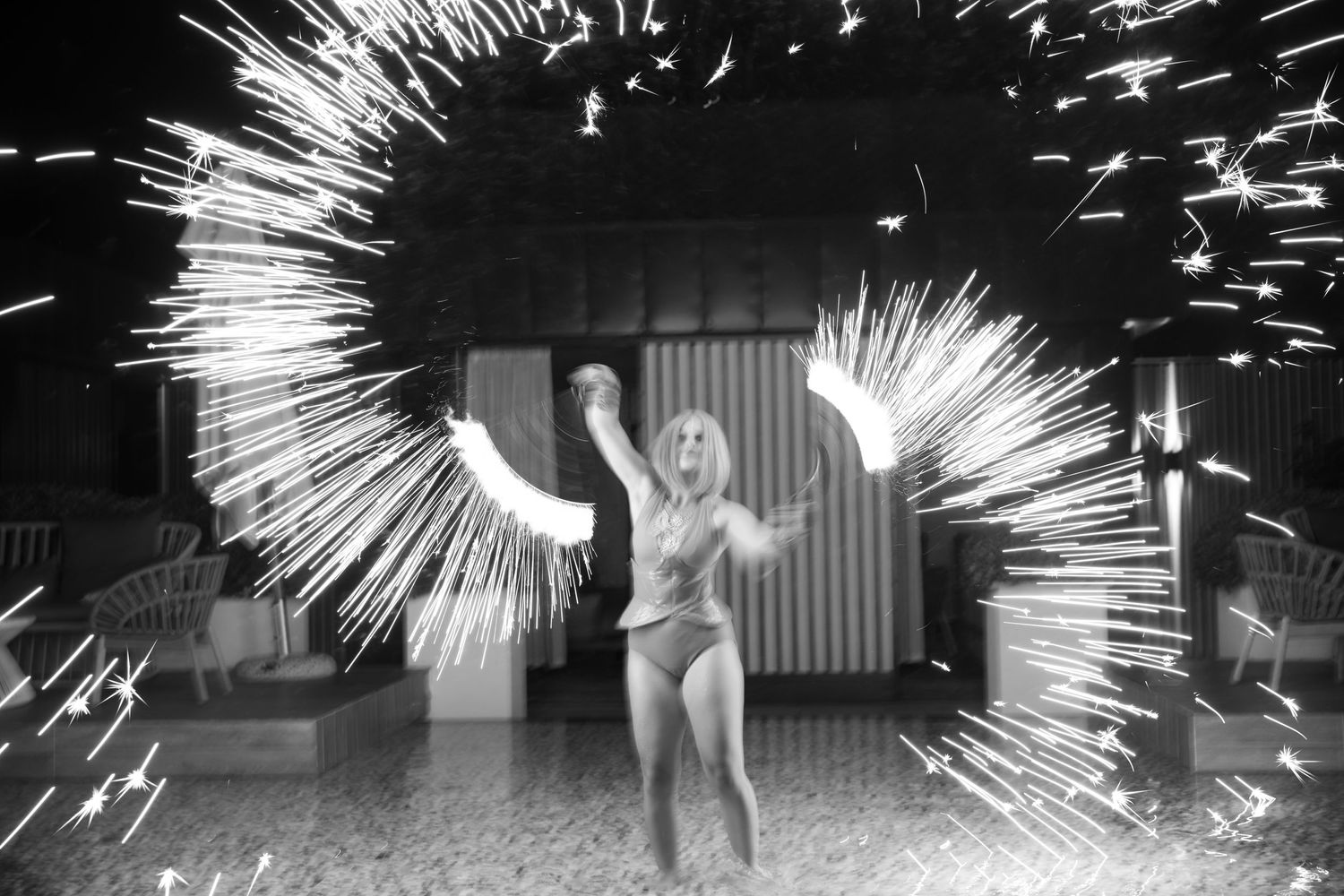 Black and white photo of sparklers and light trails creating dramatic circular patterns around a figure in motion.