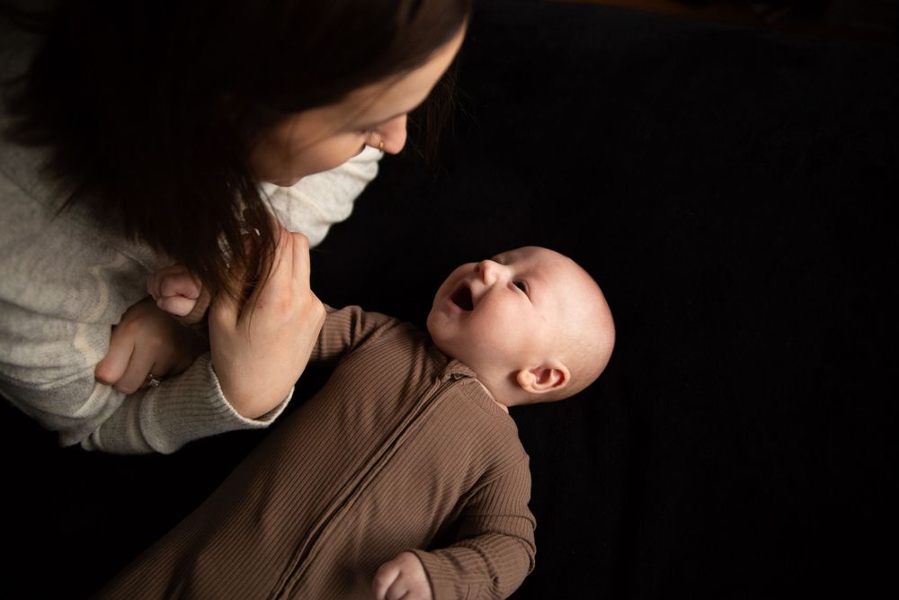 Parent and baby share an intimate moment against dark background with soft lighting.