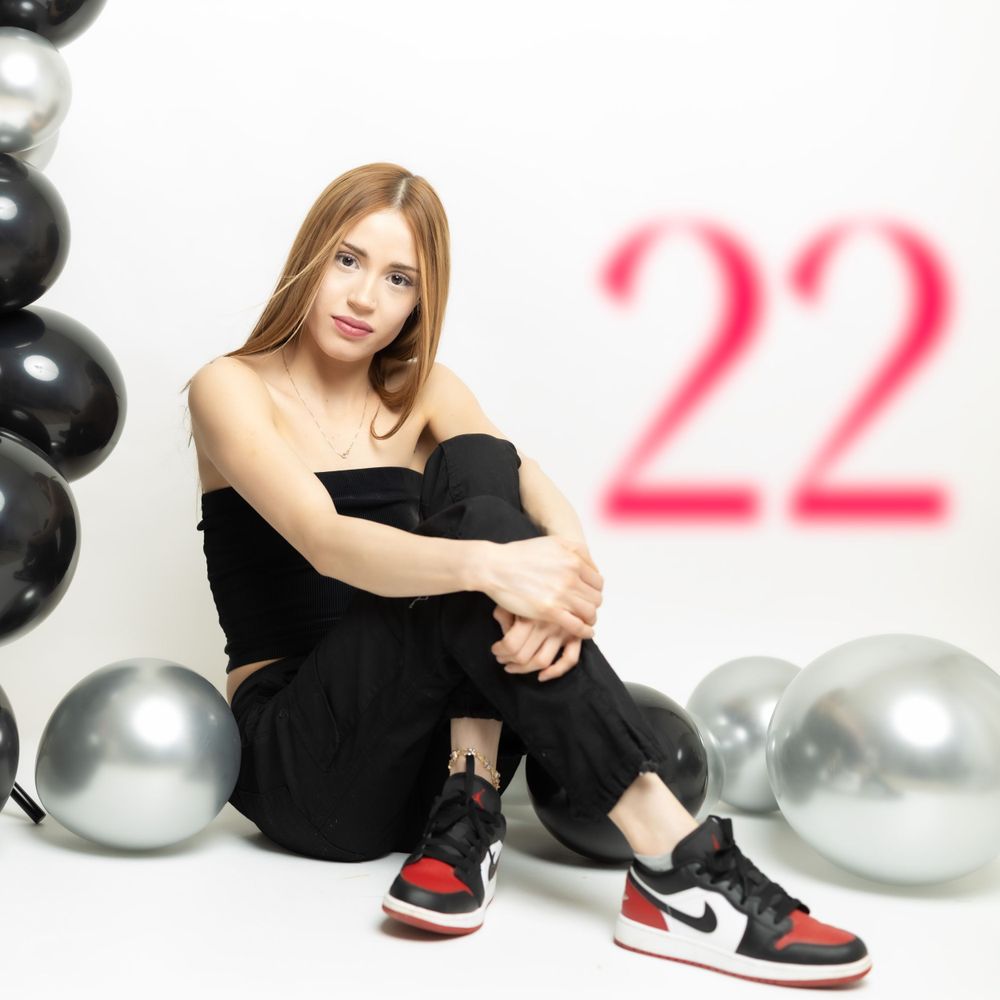 Casual birthday photo featuring Nike sneakers and balloon decorations with '22' in the background.