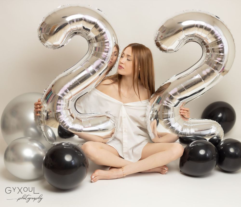Birthday photoshoot with silver number 22 balloons and black and silver balloon decorations.