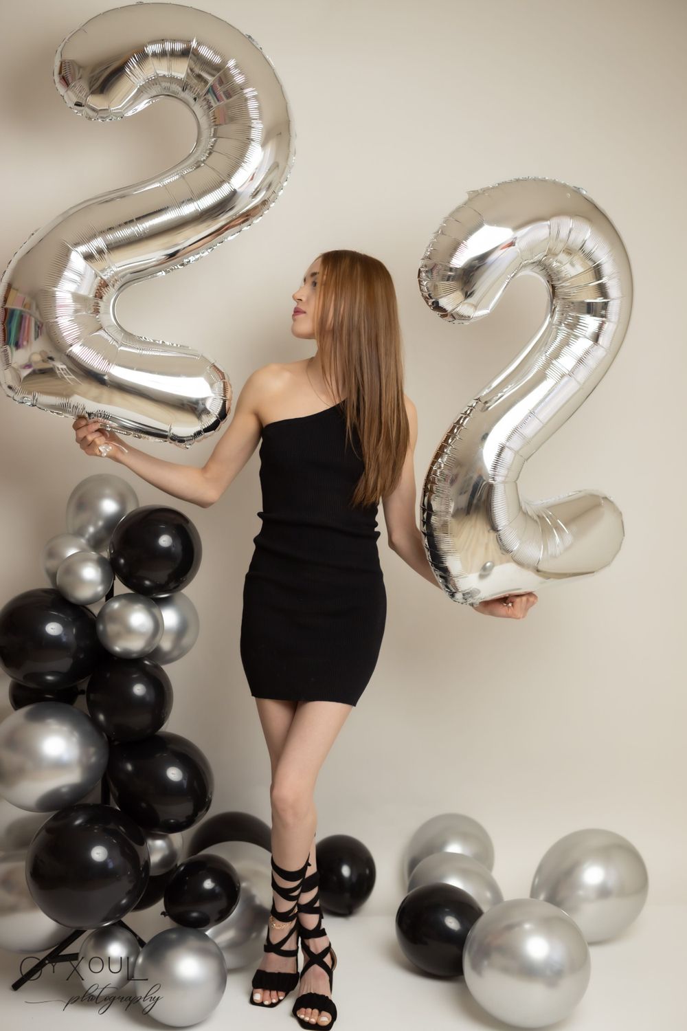 Birthday photoshoot with large silver '22' balloons and black and silver balloon decorations.