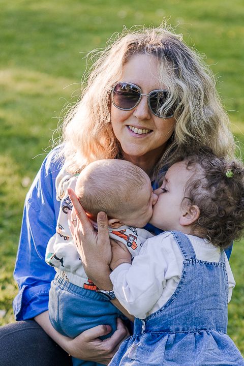 A tender family moment captured in warm sunlight as they embrace and snuggle together outdoors.