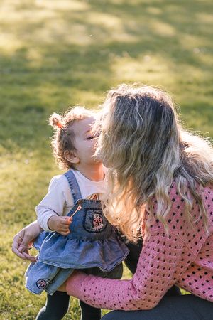 Intimate family moment captured in golden sunlight on grassy hill.