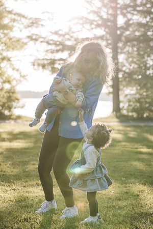 Parent and child playing together on grass in warm afternoon sunlight.