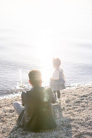 Family silhouettes sit together on a peaceful beach during golden hour.