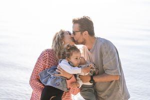 A family shares intimate moments together on a beach during golden hour.
