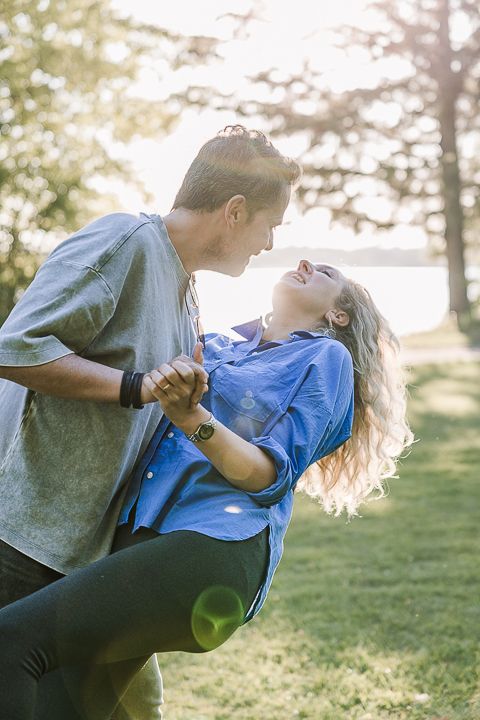 A couple dancing and twirling in a sunlit park with joyful expressions.