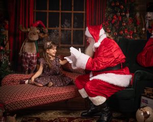 Cozy Christmas setting with plush toys and decorated tree by arched window.