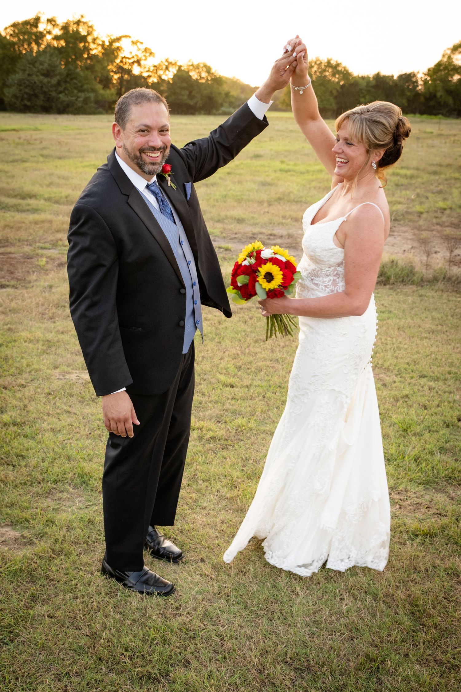 A joyful couple raises their hands in celebration during their outdoor wedding.