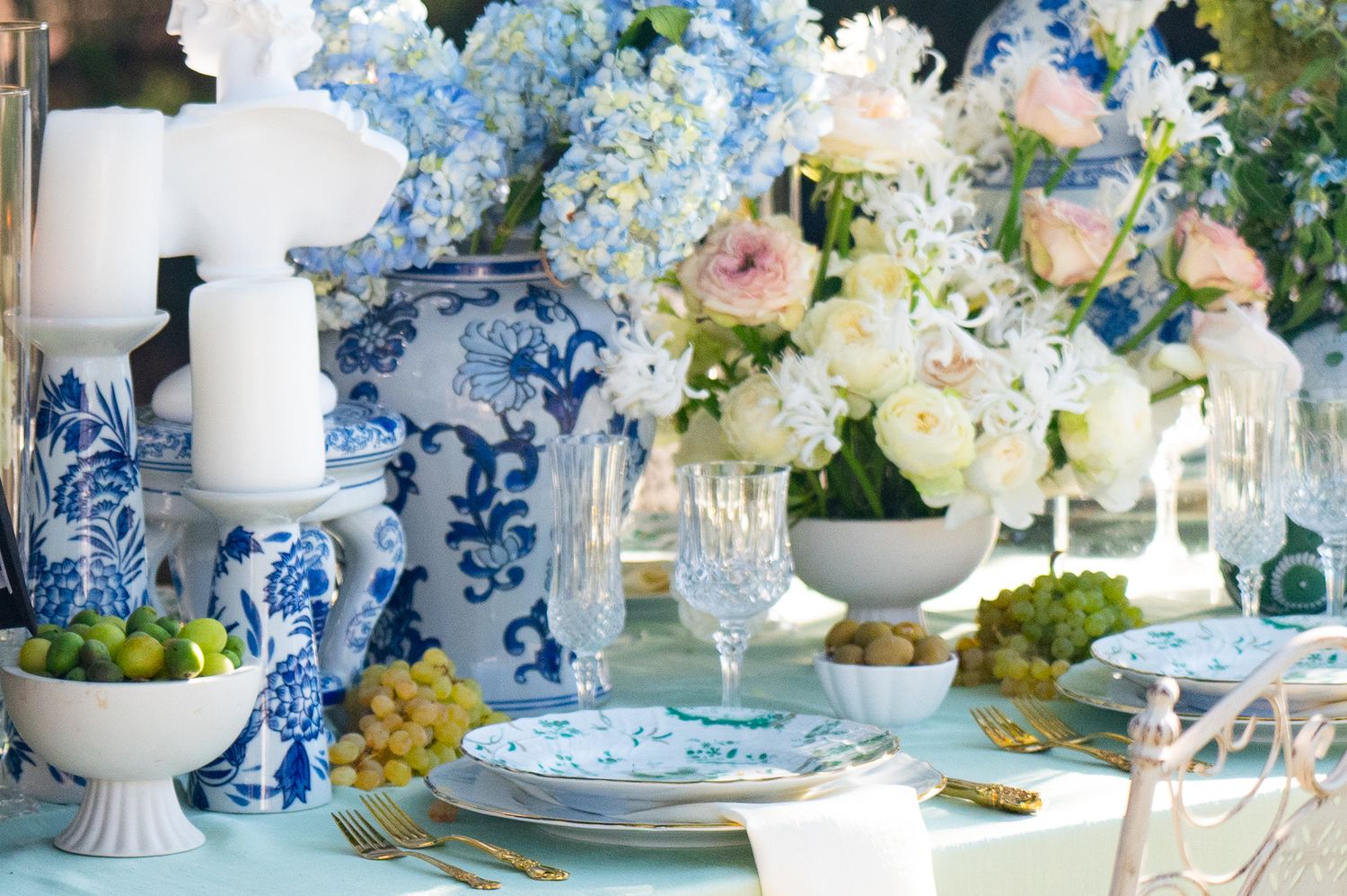 Elegant table setting with blue and white chinoiserie vases, hydrangeas, and crystal glassware for formal dining.